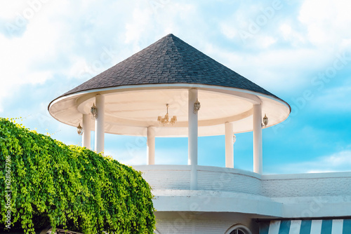 The upper part of the tiled gazebo rotunda. Beautiful dome made of concrete. Pointer to cardinal points on roof. Construction technology using modern materials. Conical dome decorated with lanterns. photo