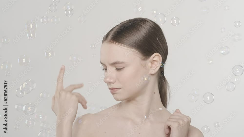 Beautiful young brunette model looking at flying soap bubbles. Slow motion HDR BT2020 HLG Material. Beautiful young brunette model looking at flying soap bubbles. Slow motion HDR BT2020 HLG Material.