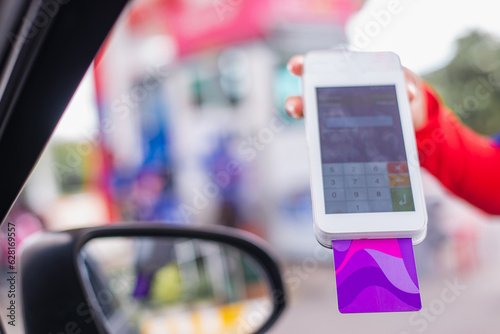 Man using a credit card to pay for gas while seated in his vehicle..