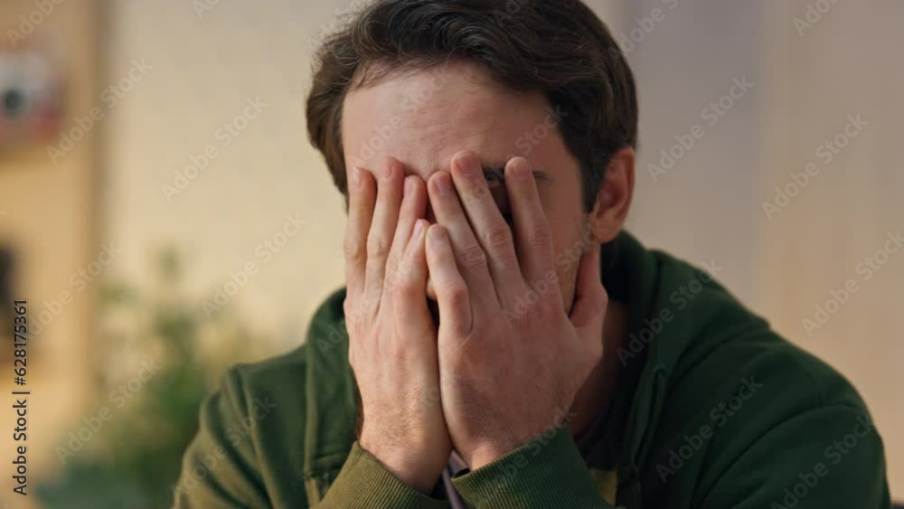 Disappointed man covering face palm in office closeup. Tired creator worried