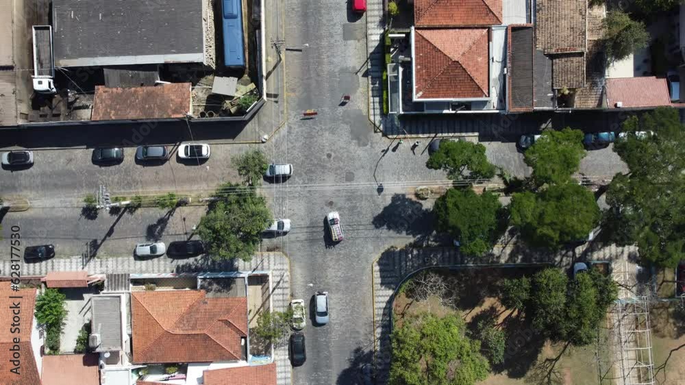 Cruzamento de trânsito de carros em um bairro residencial captada do alto por um drone em um dia de sol. 