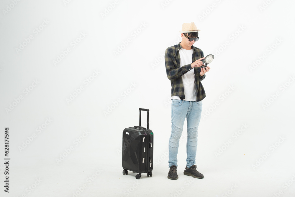 Happy asian man holding passport and tickets, ready to travel, sitting near suitcase and smiling at camera over light wall. Cheerful male traveller ready for vacation, on white background