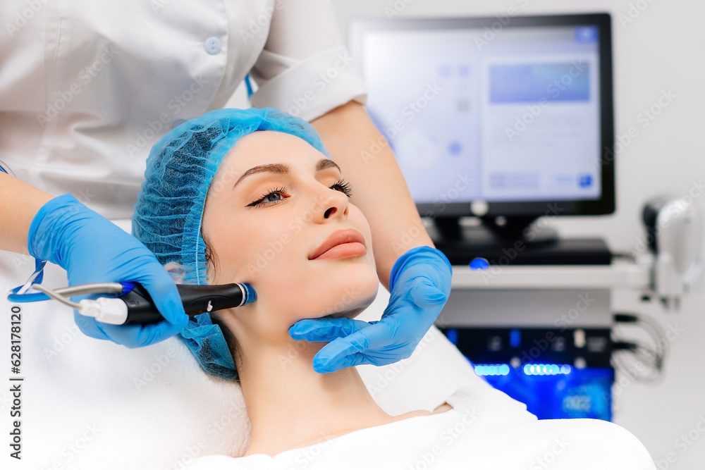 Naklejka premium Beauty therapist performing hydrafacial procedure on woman