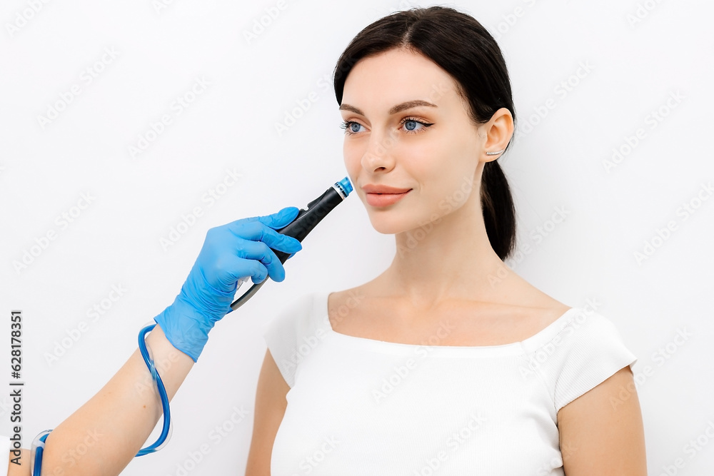 Facial skin care machine in spa clinic for anti-aging or acne treatment. The concept of aesthetic medicine, beauty tools, latest technologies in beauty industry. Facial skin care machine in spa clinic for anti-aging or acne treatment. The concept of aesthetic medicine, beauty tools, latest technologies in beauty industry.