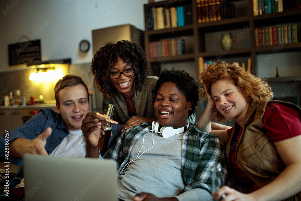 Diverse group of young people using a laptop together on the couch in the living room