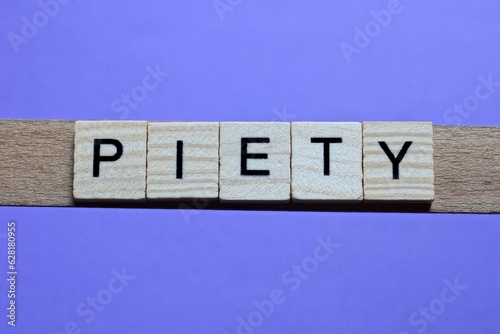 word piety made from wooden gray letters lies on a lilac background photo