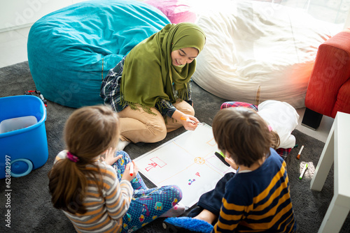 Muslim young teacher with small group of children having school learning