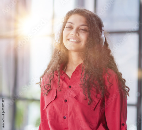 Beautiful smiling young woman in headphones in modern office