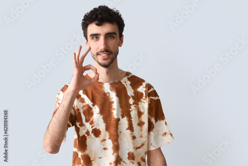 Photography Handsome man in tie-dye t-shirt showing OK on light background