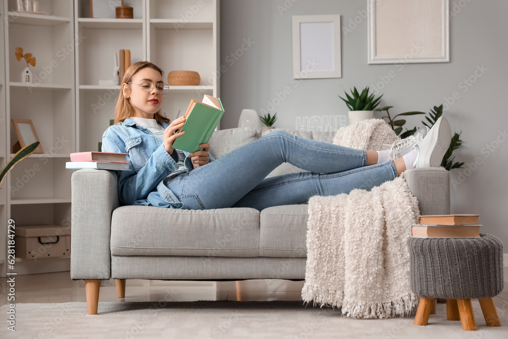 Young woman reading book on sofa at home Young woman reading book on sofa at home