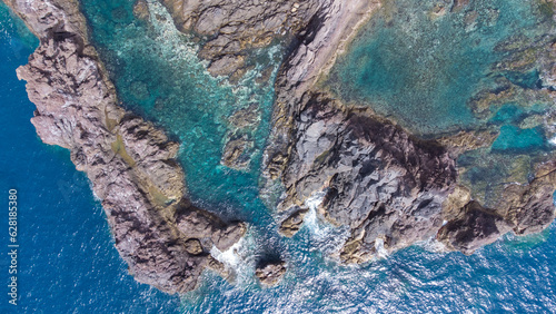 Aerial view of rocky cliffs on the coast of Madeira at the Atlantic ocean with clear blue water