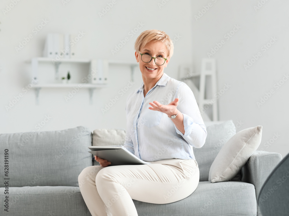 Mature psychologist with notebook sitting in office