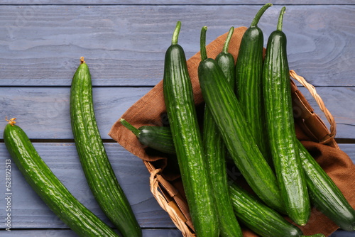 Basket with fresh cucumbers on grey wooden background, closeup