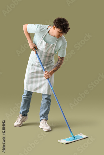 Young man with mop on green background