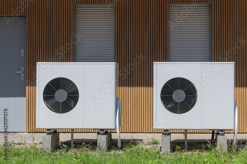 Front view of air source heat pumps in front of a modern house.