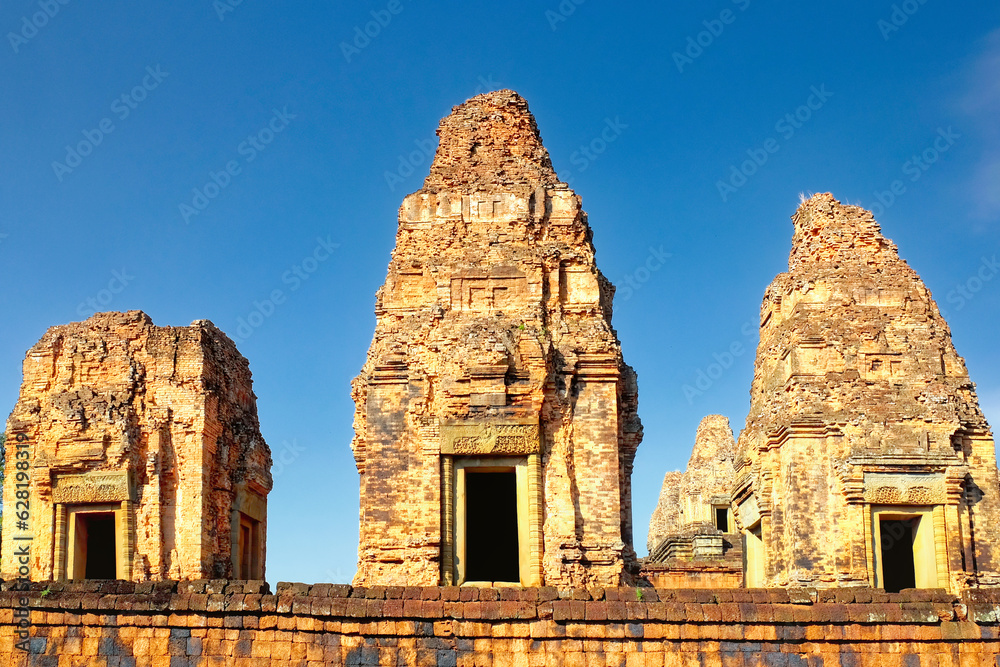 High-resolution image capturing the three monumental brick towers of the Pre Rup temple, standing proudly under the cloudless blue sky, reflecting Khmer architectural style. High-resolution image capturing the three monumental brick towers of the Pre Rup temple, standing proudly under the cloudless blue sky, reflecting Khmer architectural style.