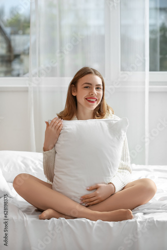 Beautiful young woman in beige tights and with pillow sitting on bed Free Download Beautiful young woman in beige tights and with pillow sitting on bed - GFXLoad
