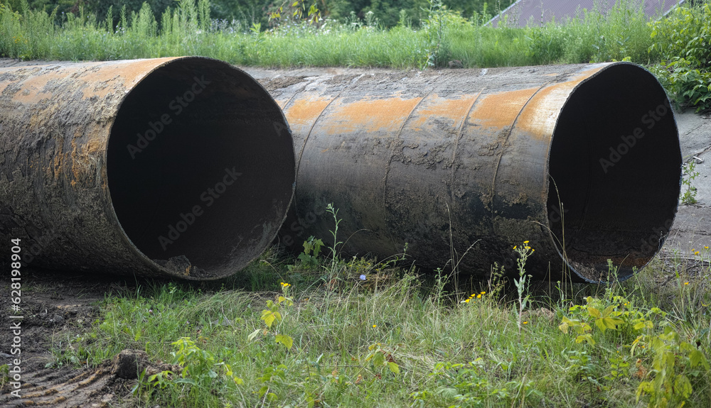 Two rusty old pipes laying on grass Two rusty old pipes laying on grass