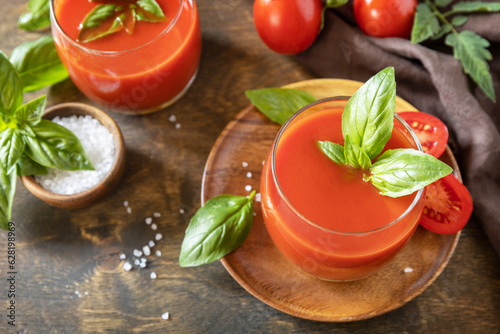 Vegetable tomato drink for a healthy diet. Glasses of fresh tomato juice with tomatoes, salt on wooden table.