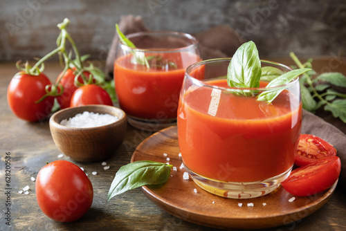 Glasses of fresh tomato juice with tomatoes, salt on wooden table. Vegetable tomato drink for a healthy diet.