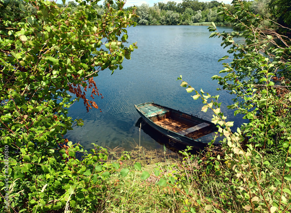 Altes, verlassenes, rostiges Ruderboot am Ufer von einem idyllischen kleinen See im Sommer. Altes, verlassenes, rostiges Ruderboot am Ufer von einem idyllischen kleinen See im Sommer.
