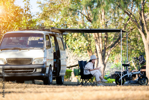Asian woman travel and camping alone by camper van at park in Thailand. Recreation and journey outdoor activity lifestyle.