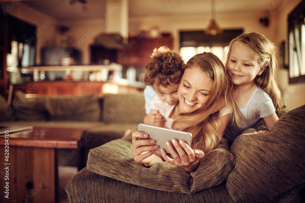 Fototapeta premium Mother and her two kids using a smart phone to take a selfie on the couch in the living room