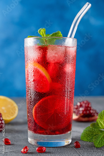Quadro su tela Iced red lemonade drink with fresh mint, sugar syrup and pomegranate juice in glass on a dark concrete background