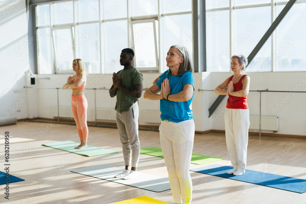 Naklejka premium Group of senior athletes raise hands to ceiling at workout