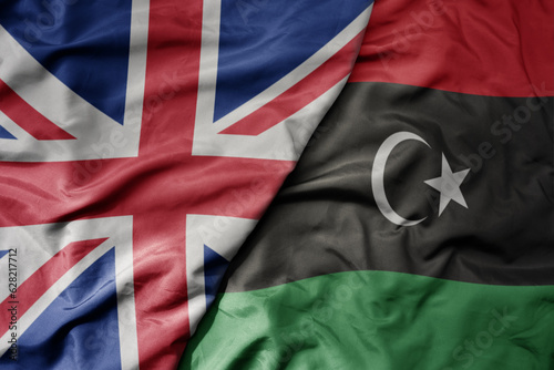 big waving national colorful flag of great britain and national flag of libya .