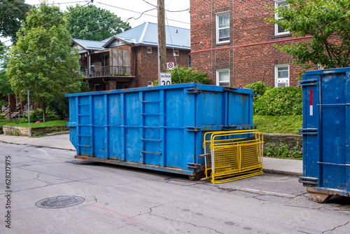 A roll-off waste dumpster outside a residential building in an older neighourhood. shot in toronto in the summer.	
