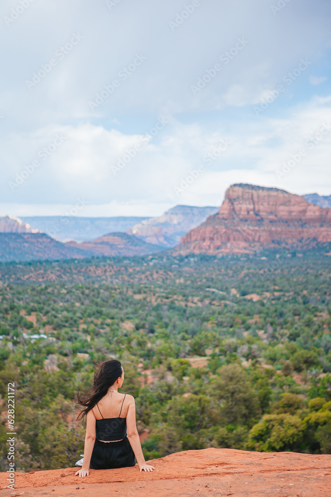 Naklejka premium Woman enjoys the view of the Sedona landscape from the top of the Bell Rock hiking trail, famous for its many energy vortexes and red rocks.