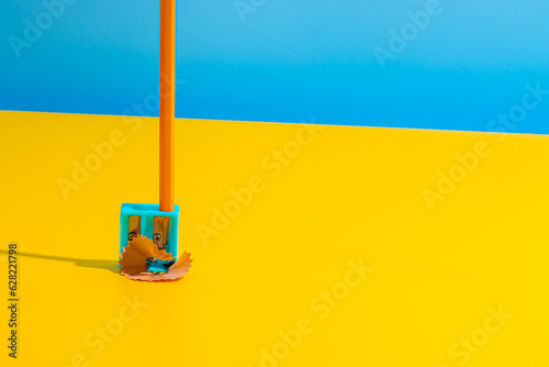 Pencil in blue sharpener on yellow table