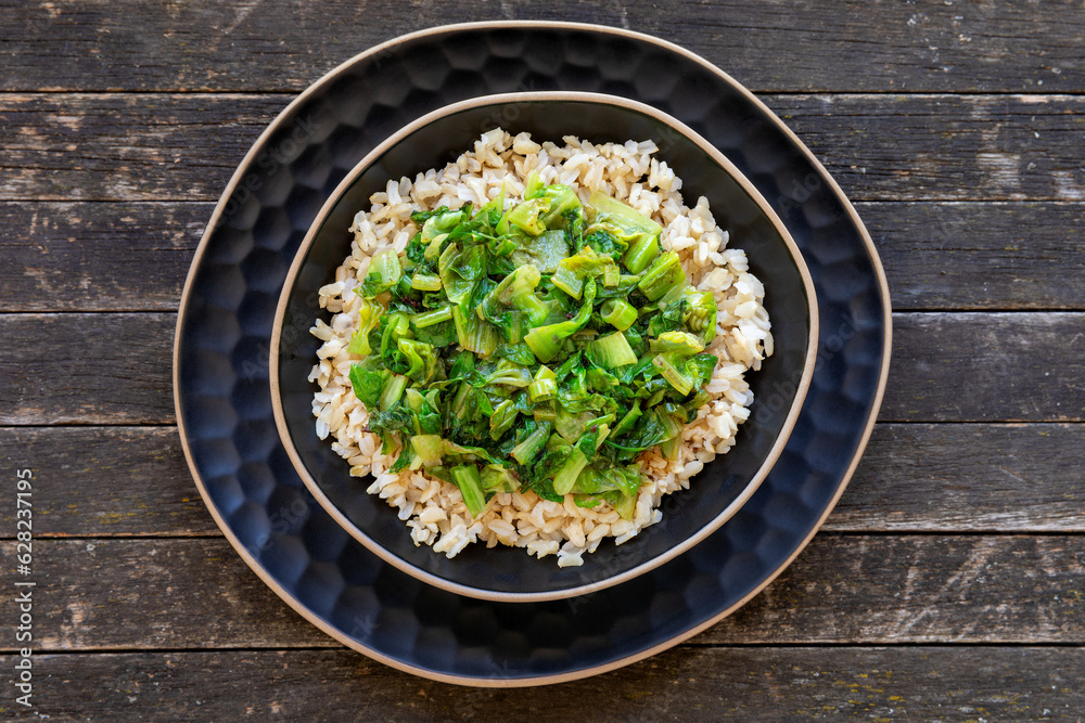 Brown rice topped with stir fry leaves of lettuce and chicory. Brown rice topped with stir fry leaves of lettuce and chicory.