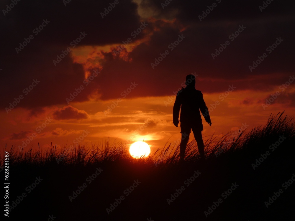 Silhouette eines Jungen auf der Düne beim Sonnenuntergang