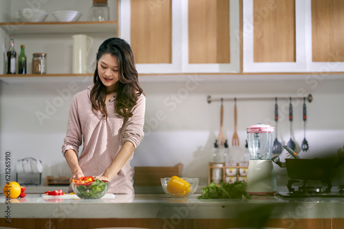 young asian woman preparing meal in kitchen at home