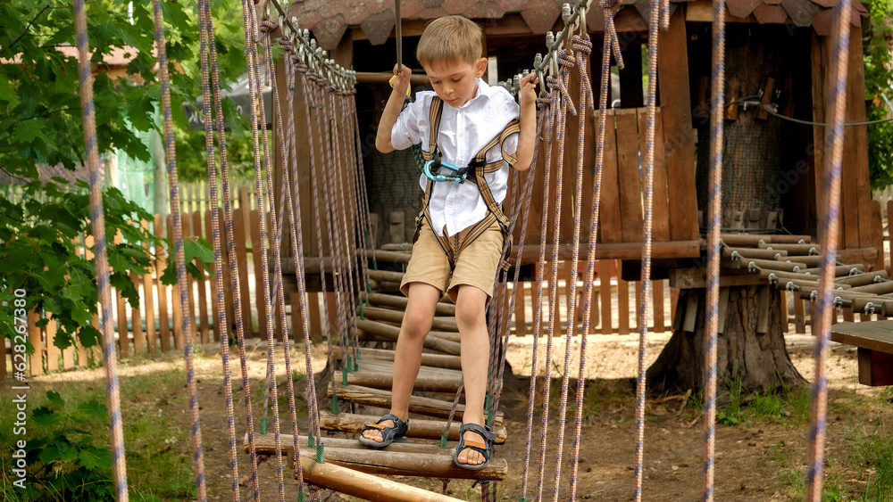 Little boy having fun at extreme adventure park in summer camp. Kids sports, summer holiday, fun outdoors, scouts. Little boy having fun at extreme adventure park in summer camp. Kids sports, summer holiday, fun outdoors, scouts.
