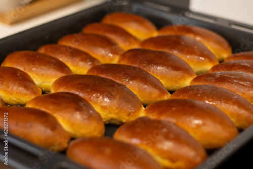 Sweet hot buns on a baking sheet. Yeast dough. Bakery in the kitchen. Homemade baking