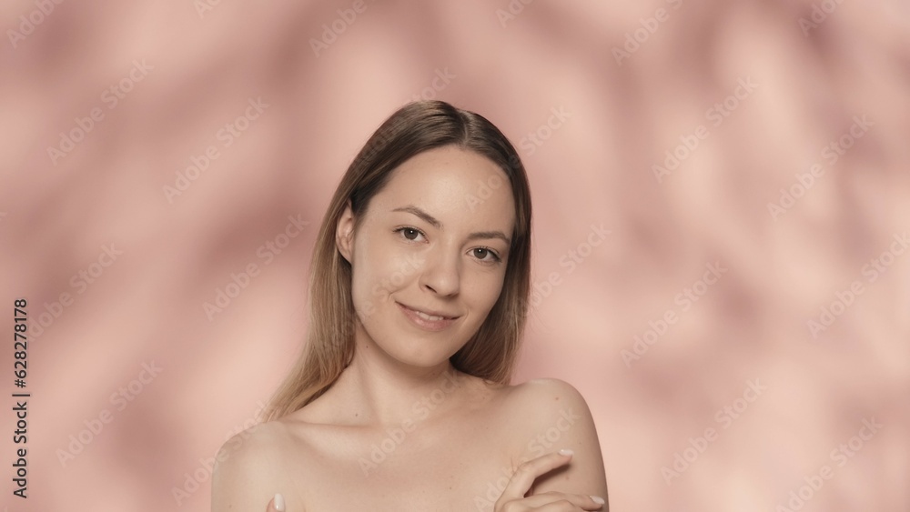 A young woman touches her shoulder, enjoying the smooth, soft skin. Portrait of a woman isolated on a pink background close up. The concept of beauty, cosmetology, skin care, spa. A young woman touches her shoulder, enjoying the smooth, soft skin. Portrait of a woman isolated on a pink background close up. The concept of beauty, cosmetology, skin care, spa.