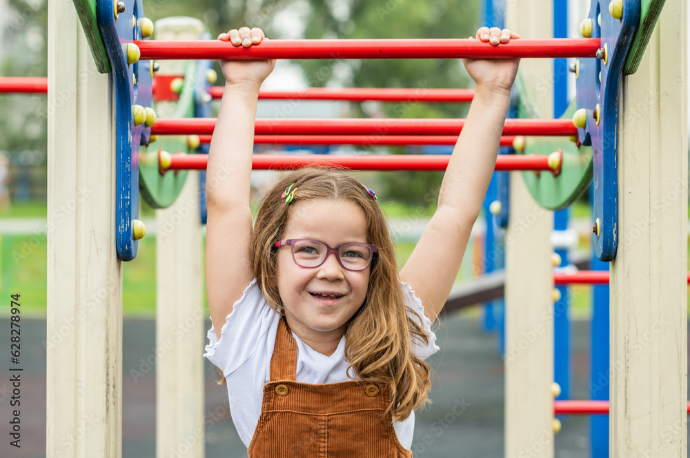 Fototapeta premium portrait of a happy smiling girl 6 years old playing on a children's playground.looks at the camera close-up. High quality photo