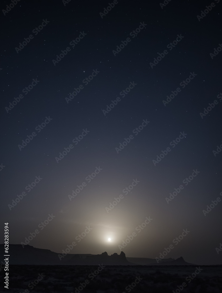 Chalk and limestone remnants in the Kazakh steppe at night against the background of the starry sky and the moon, vertical landforms after weathering in the desert