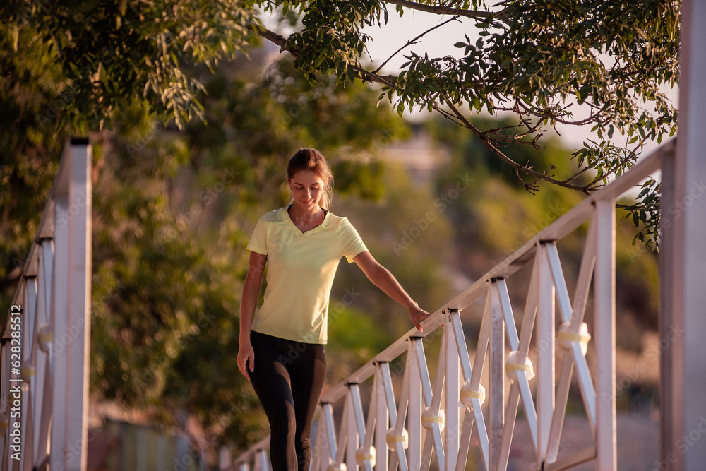Φωτογραφία Young woman in sportswear is resting after workout, walking along wooden stairs
