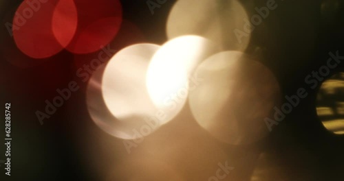 Abstract background of warm Christmas lights with large bokeh circles. Handheld shot with motion.
