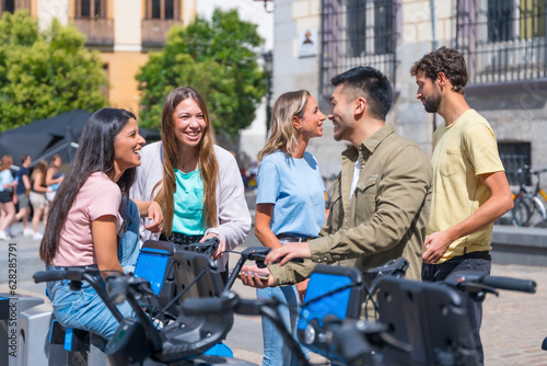 Group of multi-ethnic friends in the city renting bikes having fun on a summer afternoon