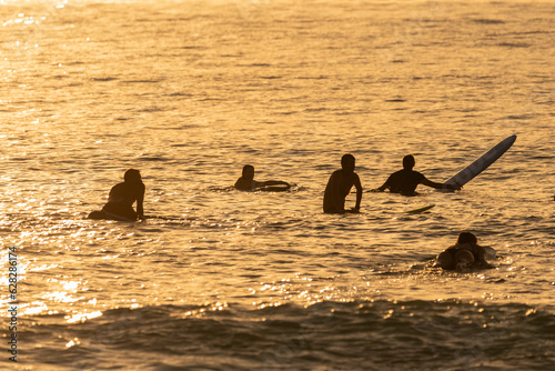 Photography silhouette of surfers against the light at sunset.