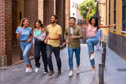 Group of multiracial friends hugging, smiling and jumping in the city, friendship concept with boys and girls