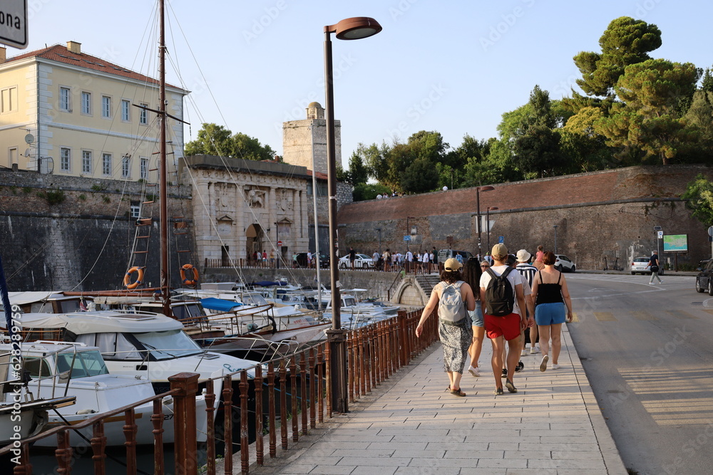 Tourists walk in the old town past the yachts in Zadar in Croatia