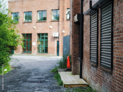 Small path in a back of an office building with security metal shutters over windows. Selective focus. Protection from brake in. Working in a dangerous city area concept.