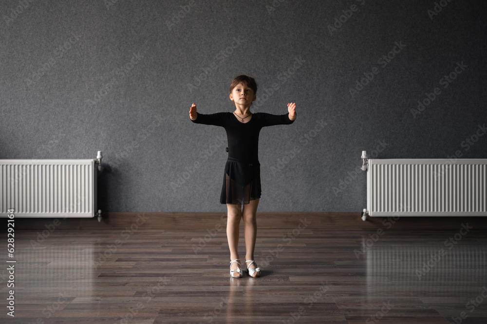 Child girl standing in black sport bodysuit in dancing studio during training posture. 4 5 years old preschool age. Healthy physical development Child girl standing in black sport bodysuit in dancing studio during training posture. 4 5 years old preschool age. Healthy physical development