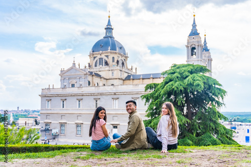 Portrait of tourist friends visiting Madrid city on summer vacation. Sitting looking at the Almudena